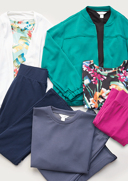 A selection of folded relaxed.RESTYLED.® clothing including a print tee, long-sleeve white sweater, bottoms, solid tees, and more.